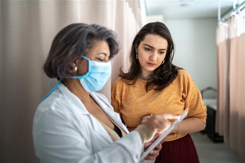 Doctora orientando a una mujer joven sobre el VPH y su prevención.
